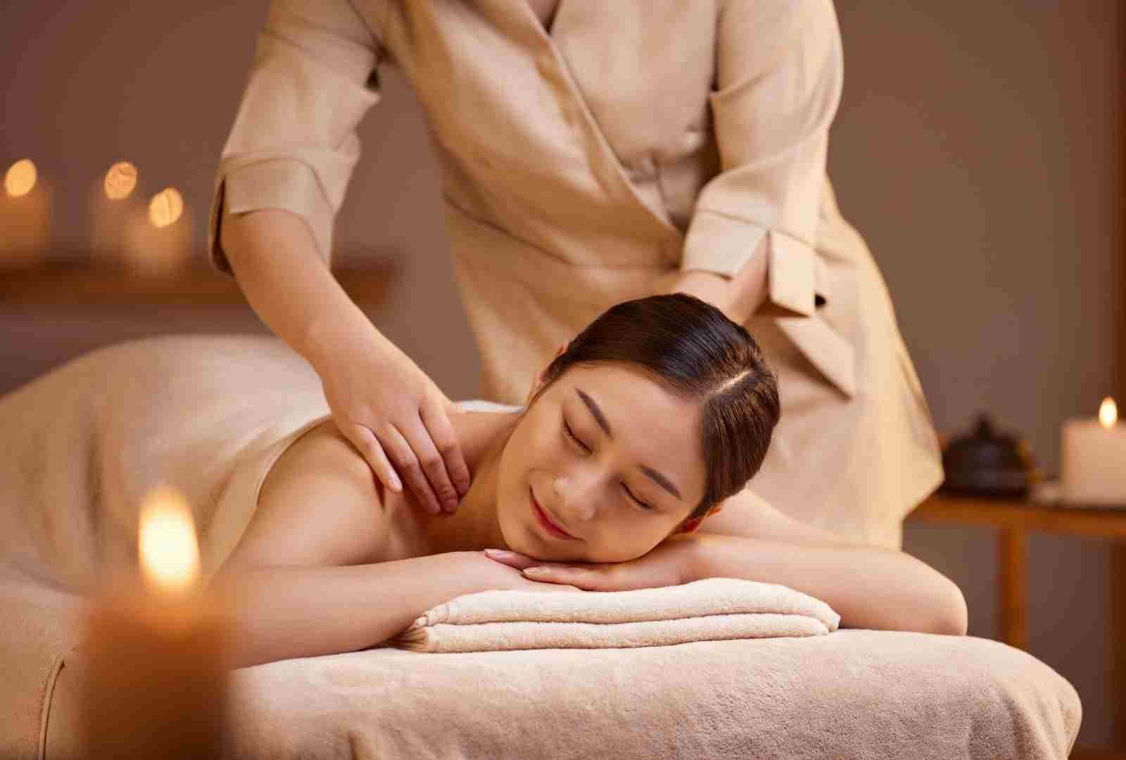 Người phụ nữ đang được massage thư giãn trong không gian với ánh nến ấm áp.