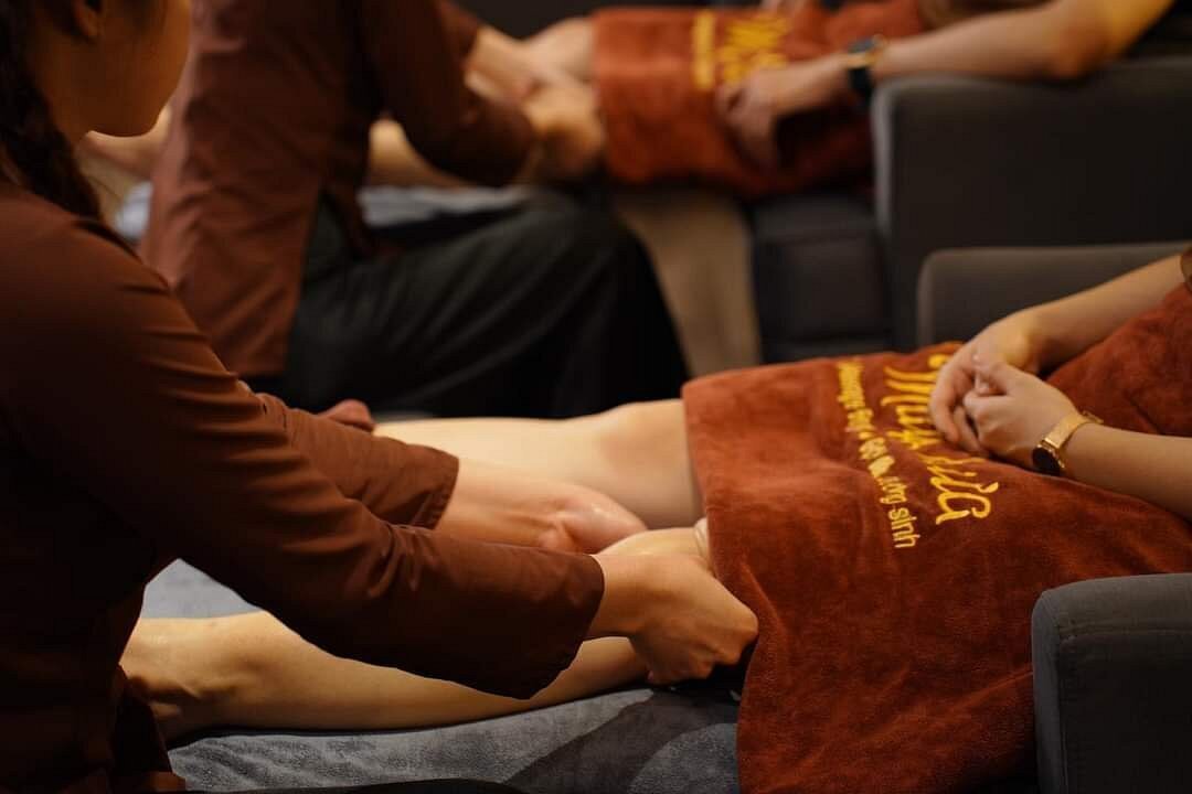 Người đang thực hiện massage chân cho khách trên ghế, với khăn màu nâu phủ lên chân.