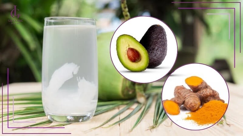 Ly nước dừa trên bàn, bên cạnh là hình ảnh quả bơ và củ nghệ.